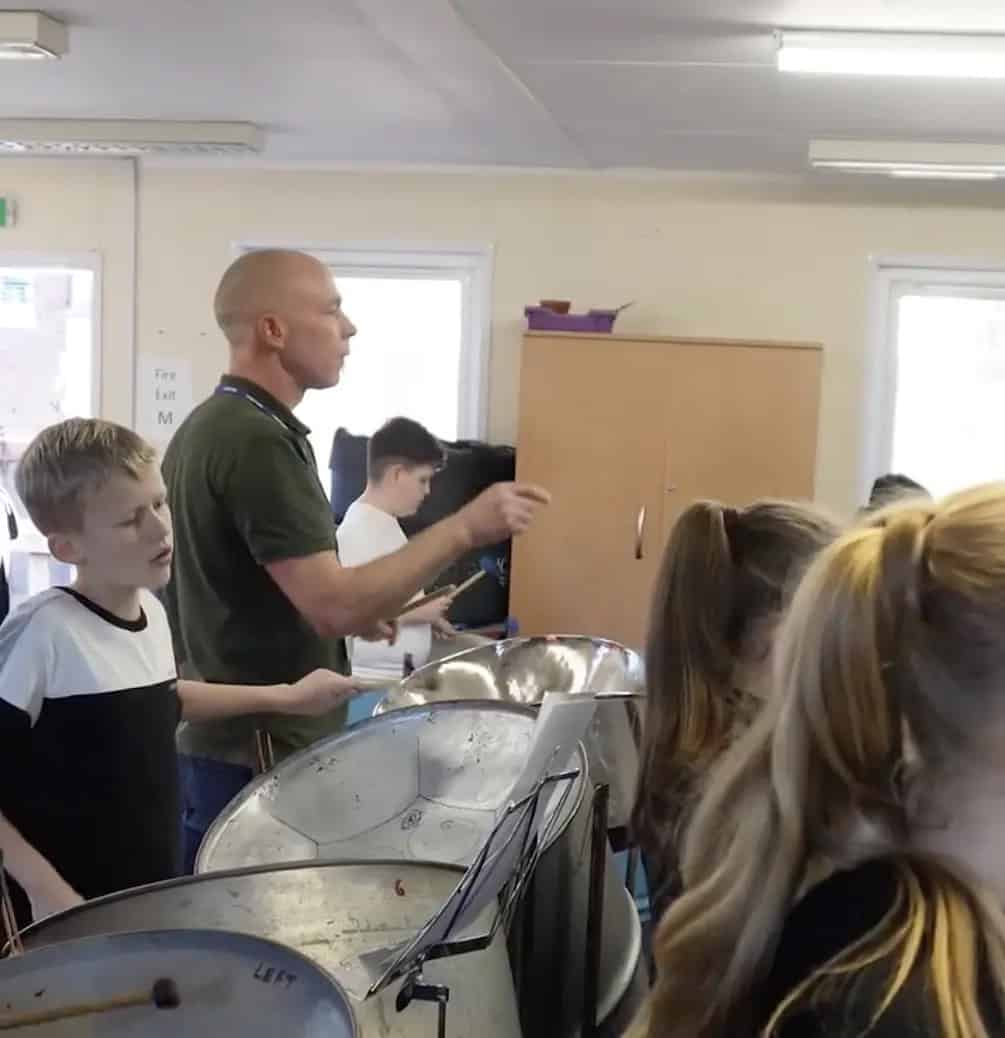 Children and teacher during a music lesson with steel pans